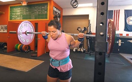 A female weightlifter prepares to do a squat.