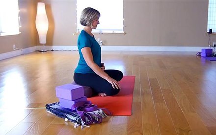 A physical therapist sitting demonstrating yoga for pain.
