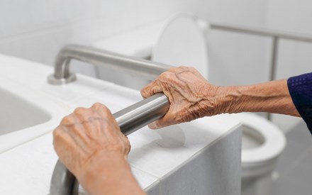 Older adult hands holding a bathroom safety rail.