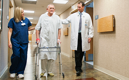 Male patient walking with a physical therapist and doctor in a hospital
