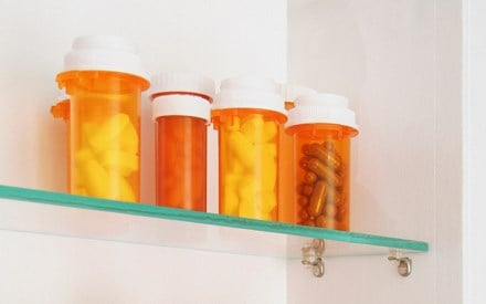 Several bottles of unused pills in a medicine cabinet.