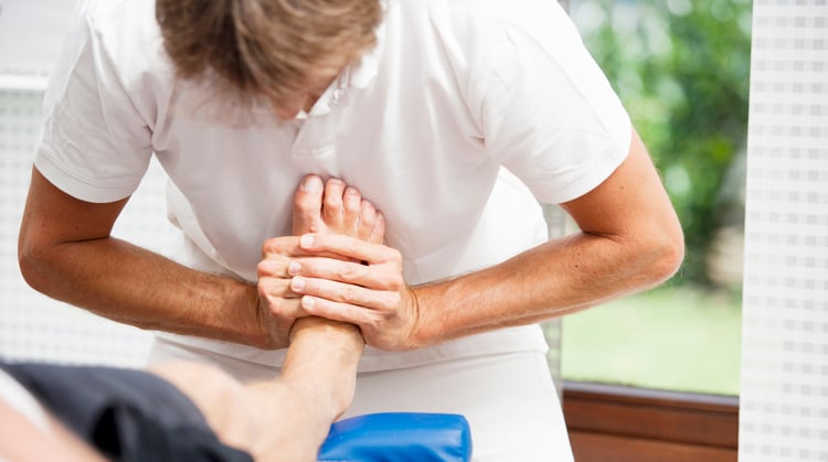 A physical therapist treats a patient with turf toe