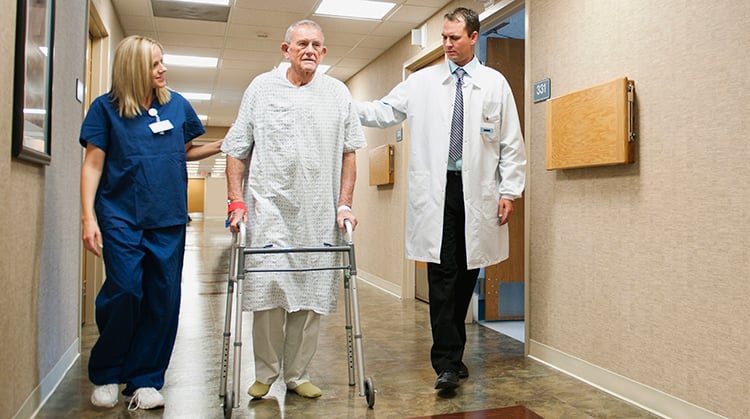 Male patient walking with a physical therapist and doctor in a hospital