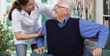 An older adult being helped to stand by a PT.