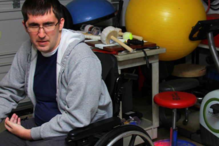 Aaron, sitting in his wheelchair in a physical therapy clinic