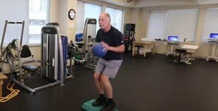 An older adult practicing basketball moves in a physical therapy clinic.