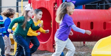 A child with down syndrome playing on the playground with friends.