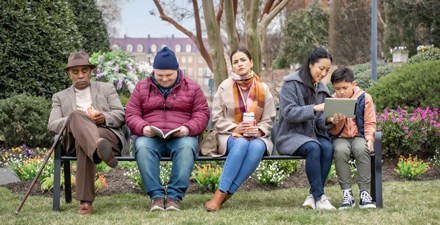 An older adult, man with down syndrome, a woman, and a mother with son sitting on a park bench.