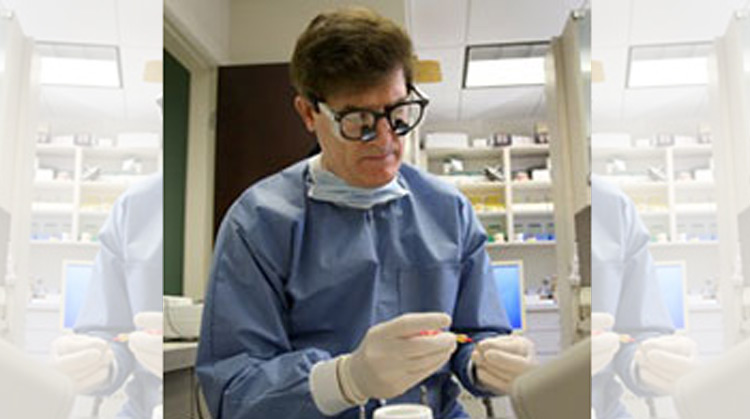 A dentist wearing magnifying glasses looking down while he works.