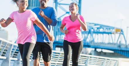 A happy black family powerwalking outdoors for exercise.