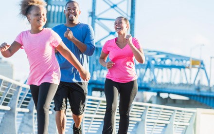 A happy black family powerwalking outdoors for exercise.