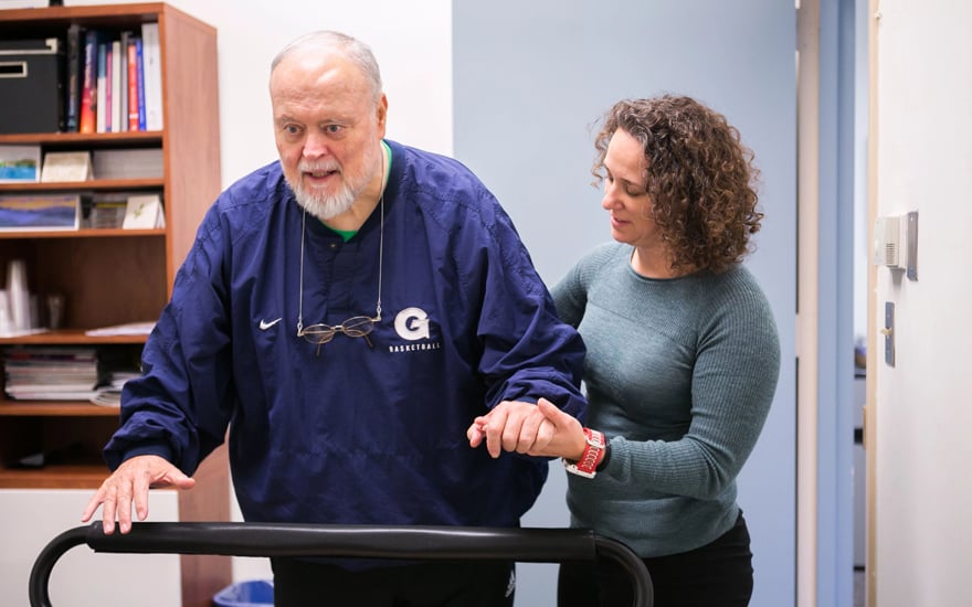 Physical therapist helping a man with walking.