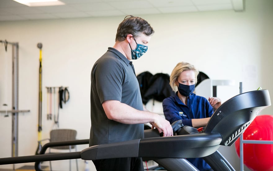 Physical therapist working with a patient on a treadmill.