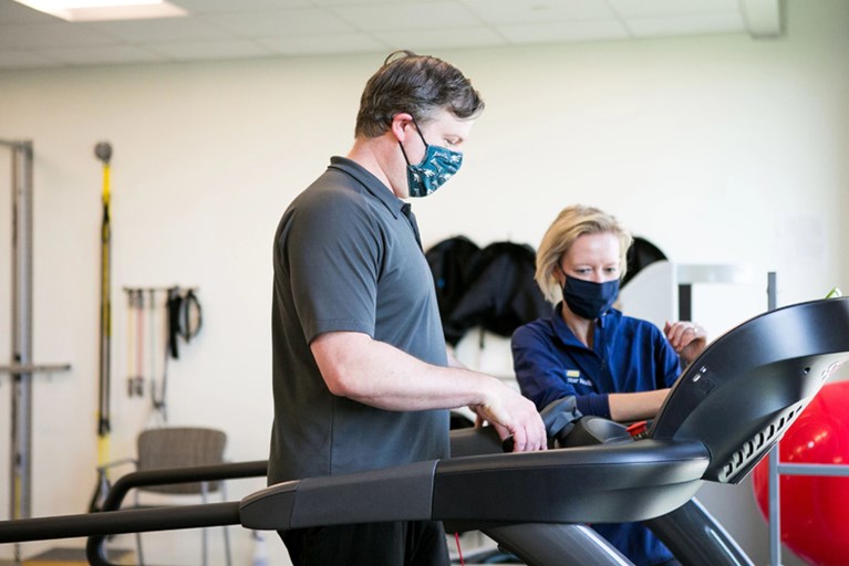 Physical therapist working with a patient on a treadmill.