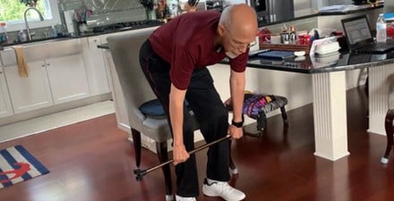 An older adult does a lower body strengthing exercise with his cane.