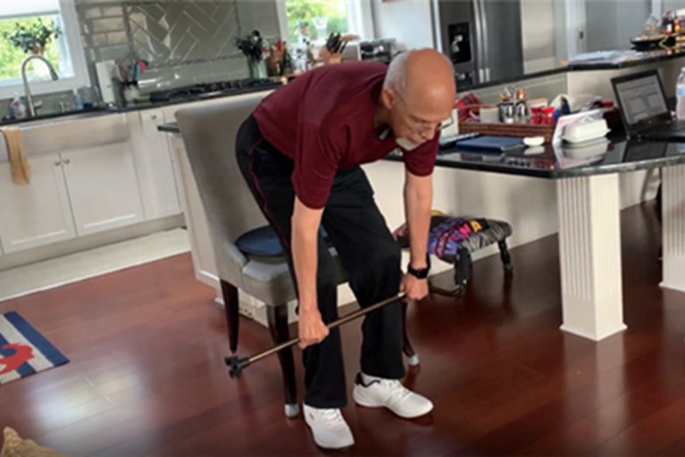 An older adult does a lower body strengthing exercise with his cane.