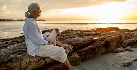 Older adult woman sitting on rocks.