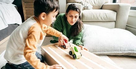 Boy and mom play together pushing cars