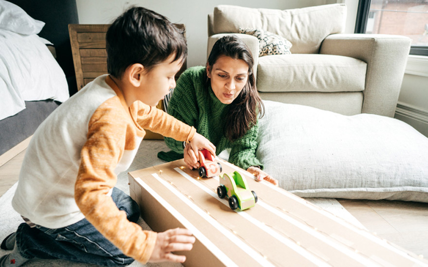 Boy and mom play together pushing cars