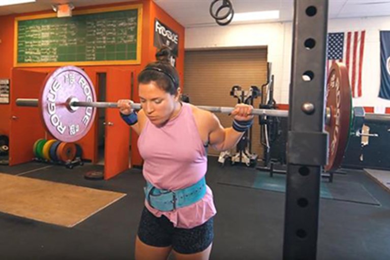 A female weightlifter prepares to do a squat.