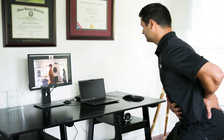 A physical therapist instructing a patient on an exercise over the computer.