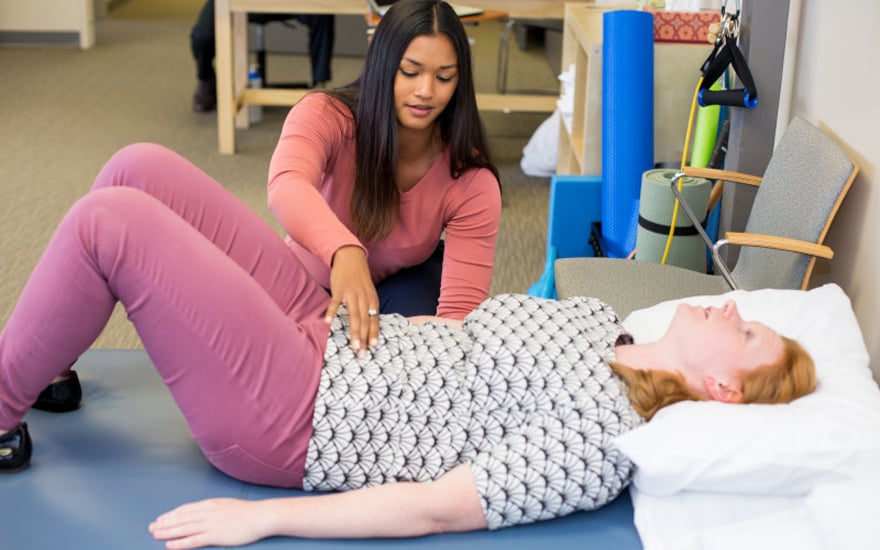 A physical therapist instructs a patient in pelvic floor exercises.