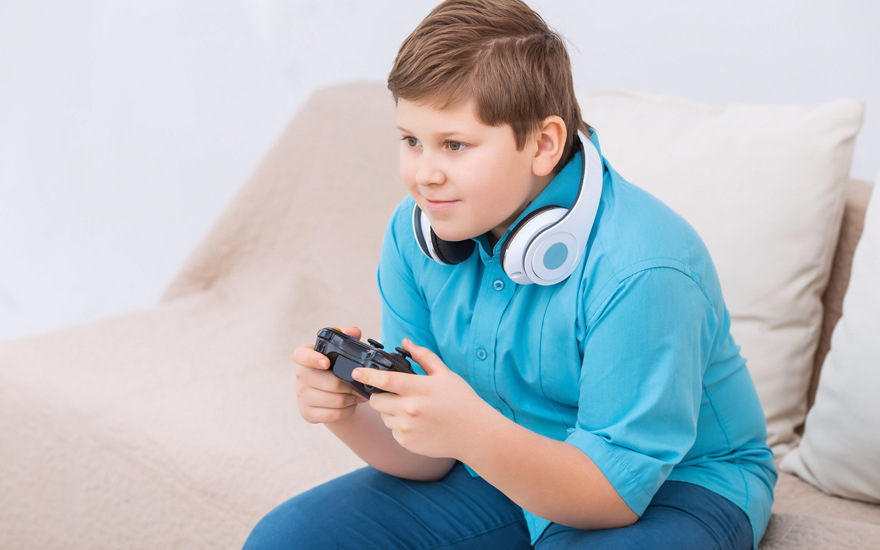 A kid playing video games on the couch.