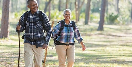 A senior couple walking with hiking sticks outdoors