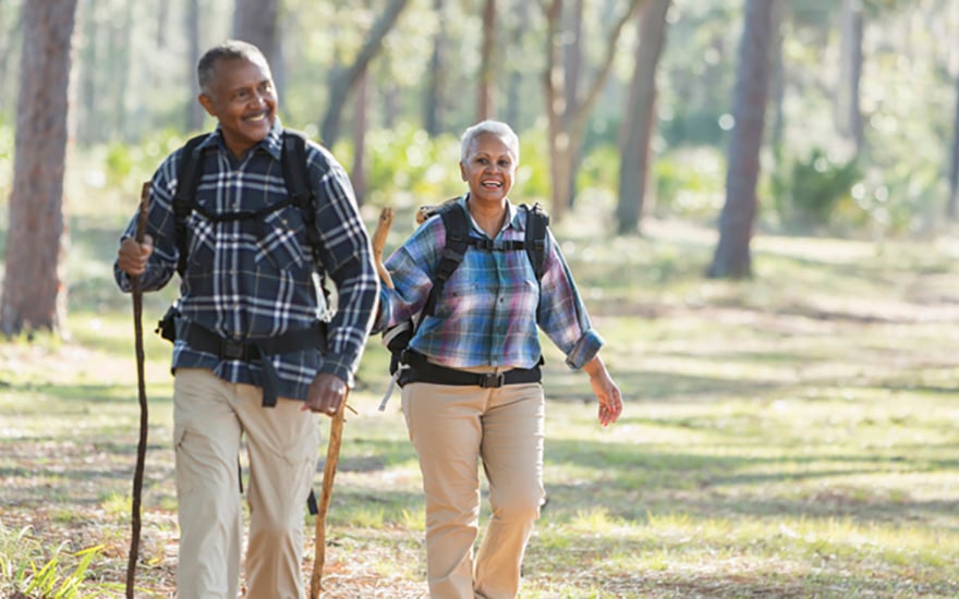 A senior couple walking with hiking sticks outdoors