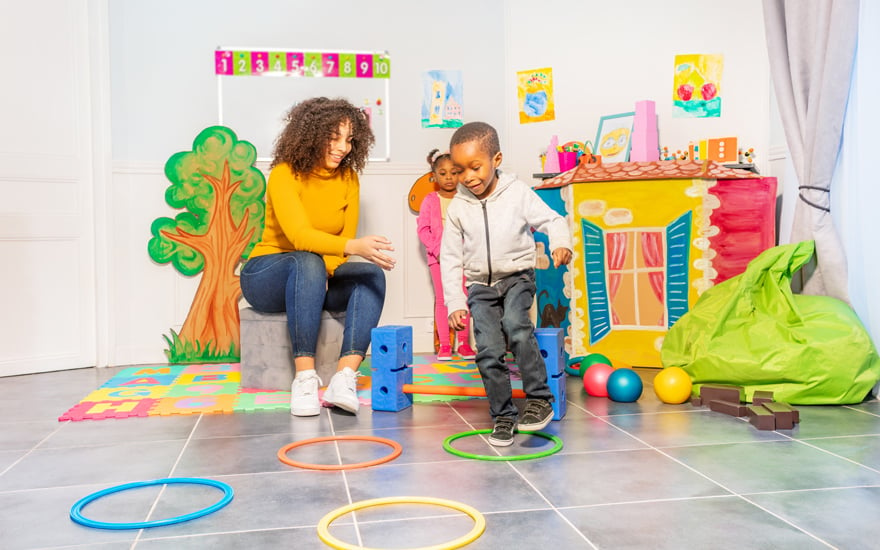 A child works on developing jumping skills while a teacher looks on