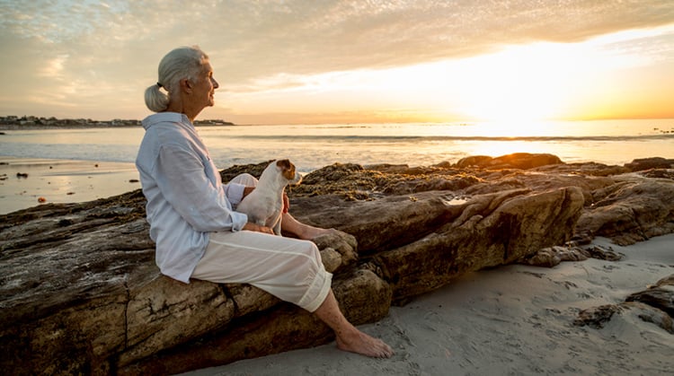 Older adult woman sitting on rocks.