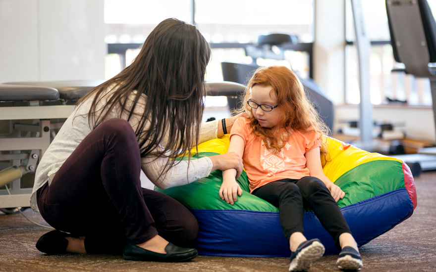 A physical therapist putting gentle presssure on a young girl's arm.