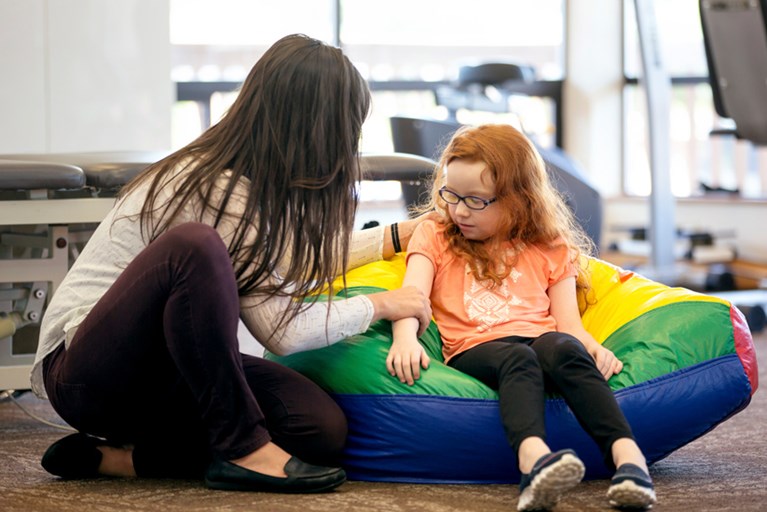 A physical therapist putting gentle presssure on a young girl's arm.