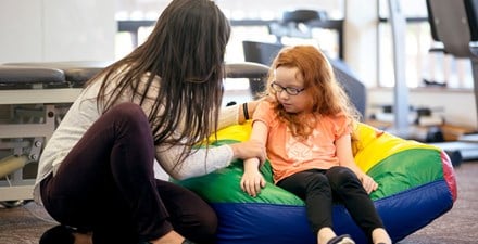 A physical therapist putting gentle presssure on a young girl's arm.