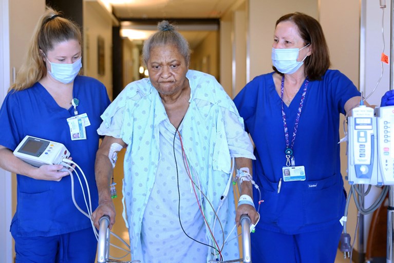 A hospital patient walks with the help of physical therapists