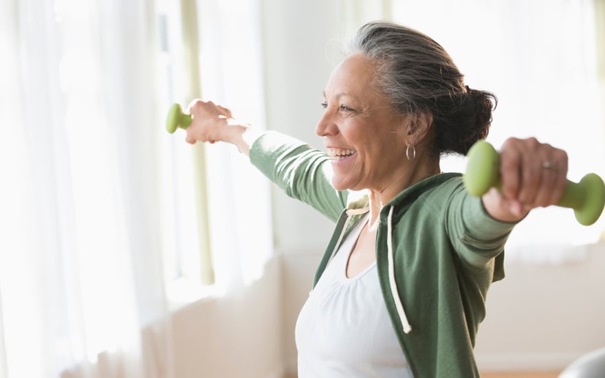 Adult female lifting light weights and smiling