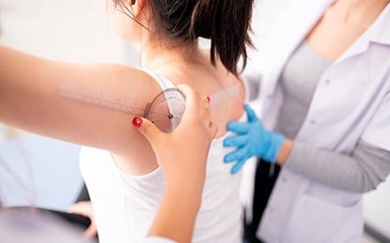 PT using a goniometer to measure patient's shoulder range of motion.