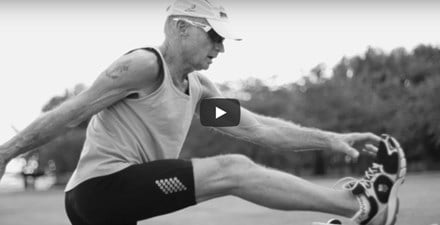 An older adult man stretching before a run.