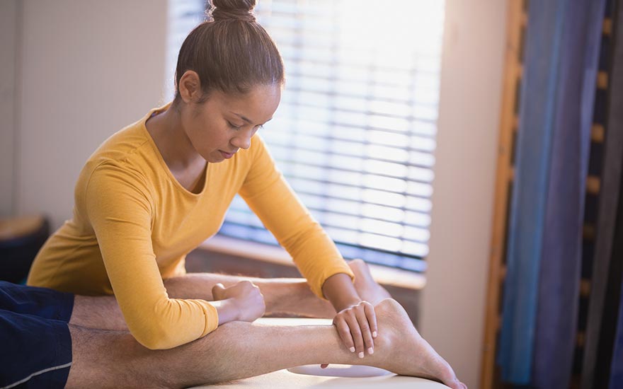 A physical therapist provides hands-on therapy on a man's calf muscles