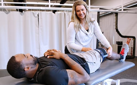 A patient lying on a treatment table as a PT provides treatment.