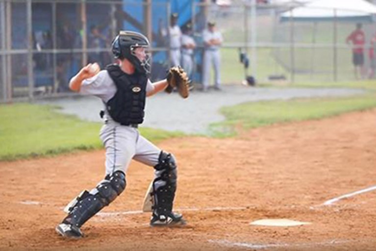 A young athlete throwing a baseball from home plate.