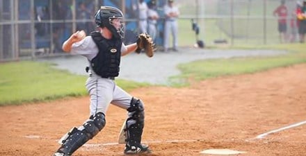 A young athlete throwing a baseball from home plate.