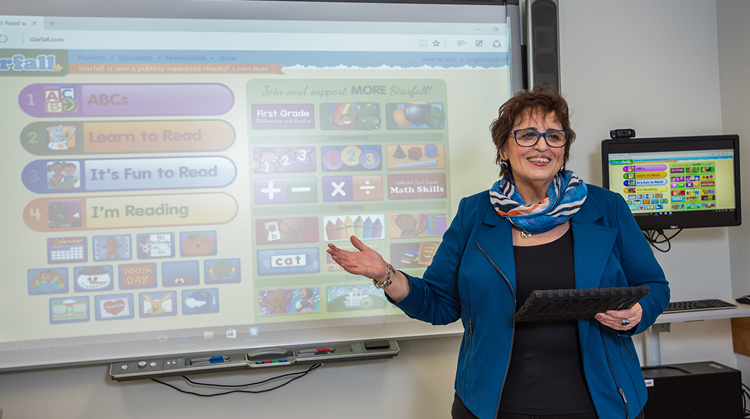 Patty standing in front of a smart board instructing a class