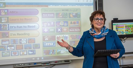 Patty standing in front of a smart board instructing a class