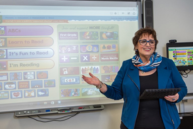 Patty standing in front of a smart board instructing a class
