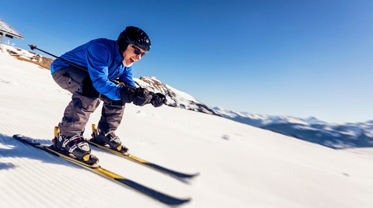 Middle-aged man skiing downhill.