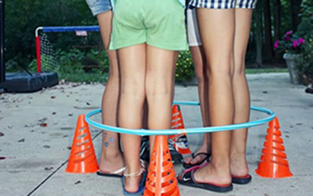 Several children with standing inside a  hula hoop facing each other.