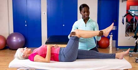 A physical therapist moves a person's knee through its range of motion.