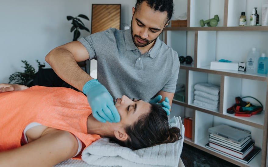 A physical therapist treats a person's jaw joint.