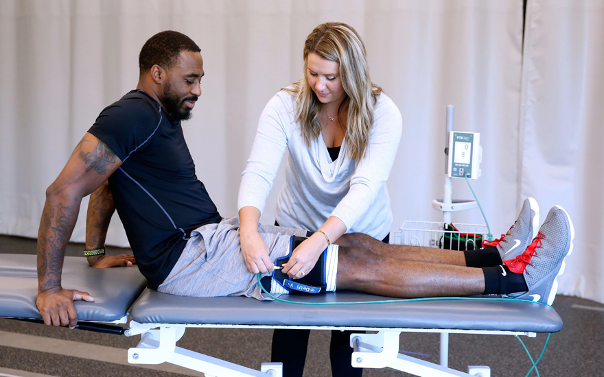 A physical therapist prepares a patient for blood flow restriction training.